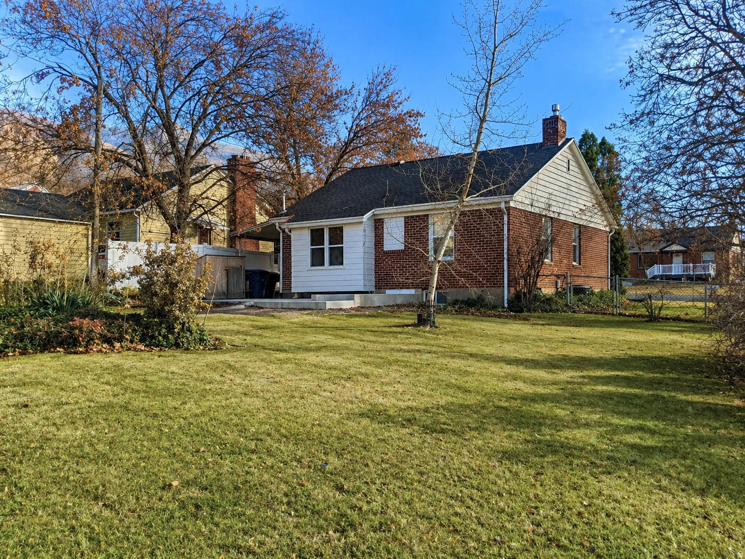Brick home featuring white siding gables, an attached chimney, and a dark roof