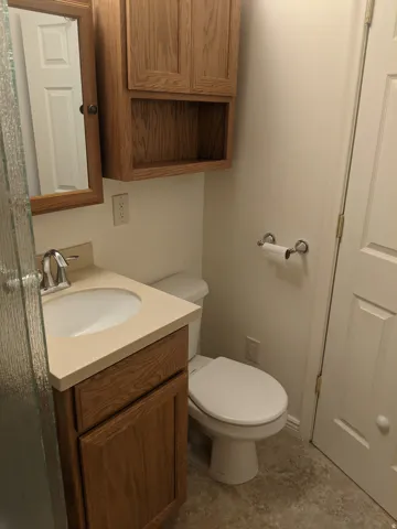 Bathroom featuring a single vanity with a countertop, an integrated sink, and wood-finish cabinetry