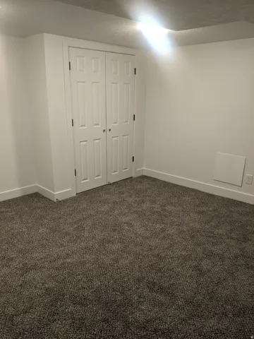 Neutral-toned wall-to-wall carpeting complements the white walls and trim