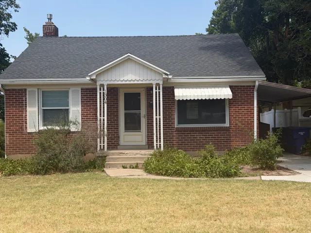 Brick facade home with a covered front porch and a dark shingle roof