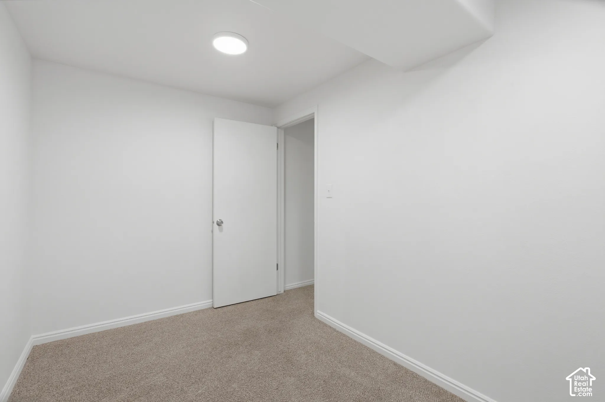 Carpeted room featuring a white interior door, recessed ceiling lighting, and white baseboards
