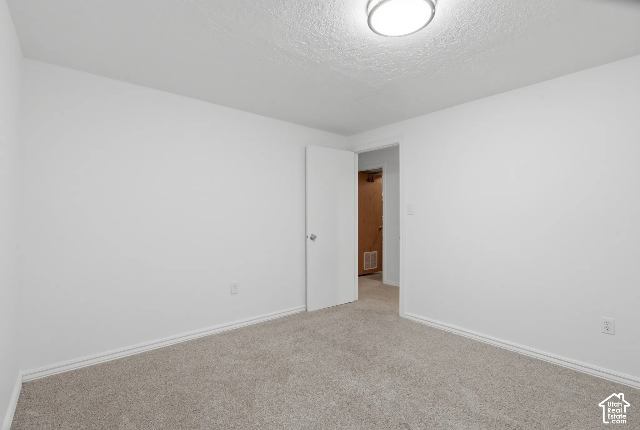 Carpeted room featuring white walls, white trim, and an overhead flush-mount light fixture