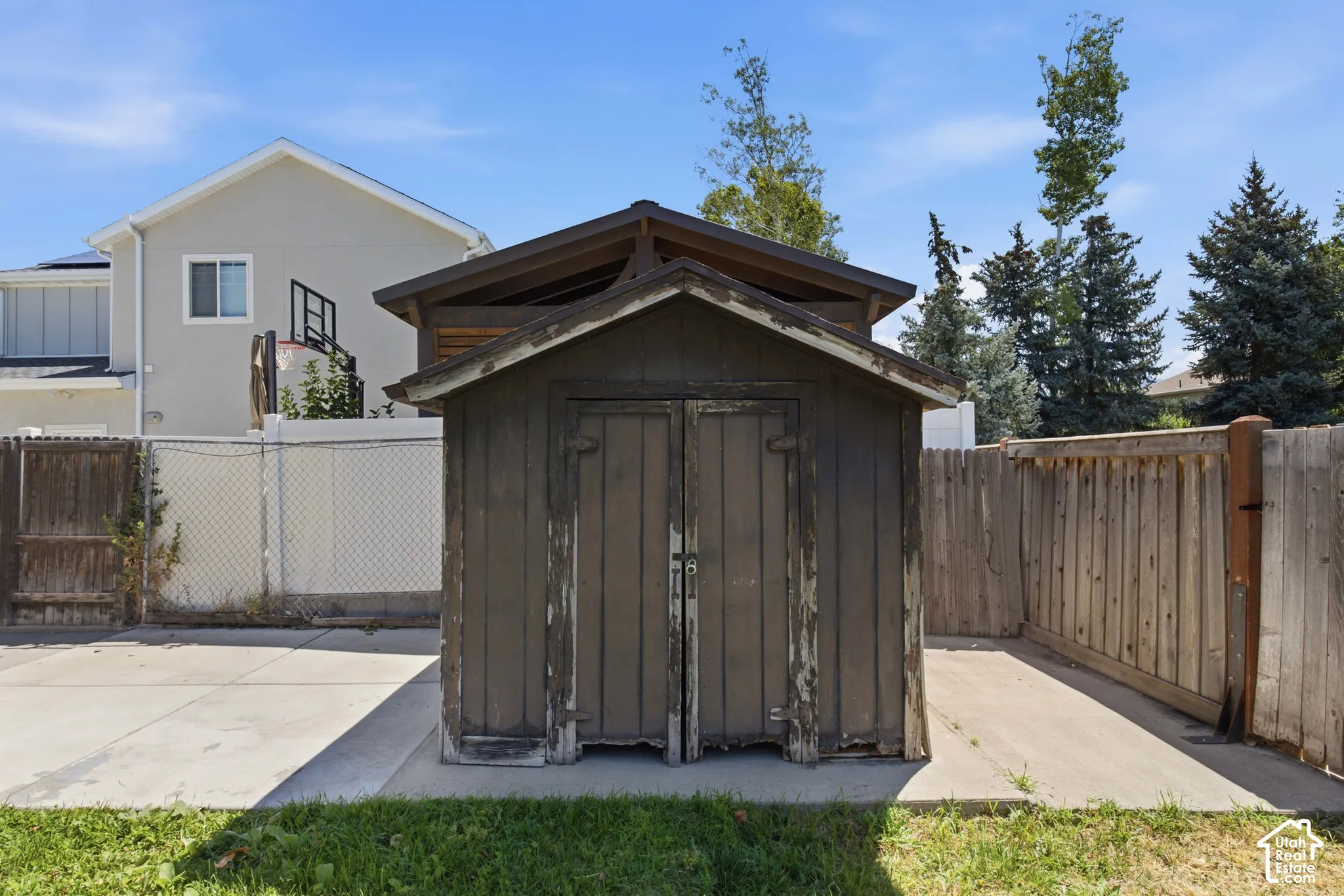Exterior storage shed with a peaked roof, two front doors, and a concrete pad