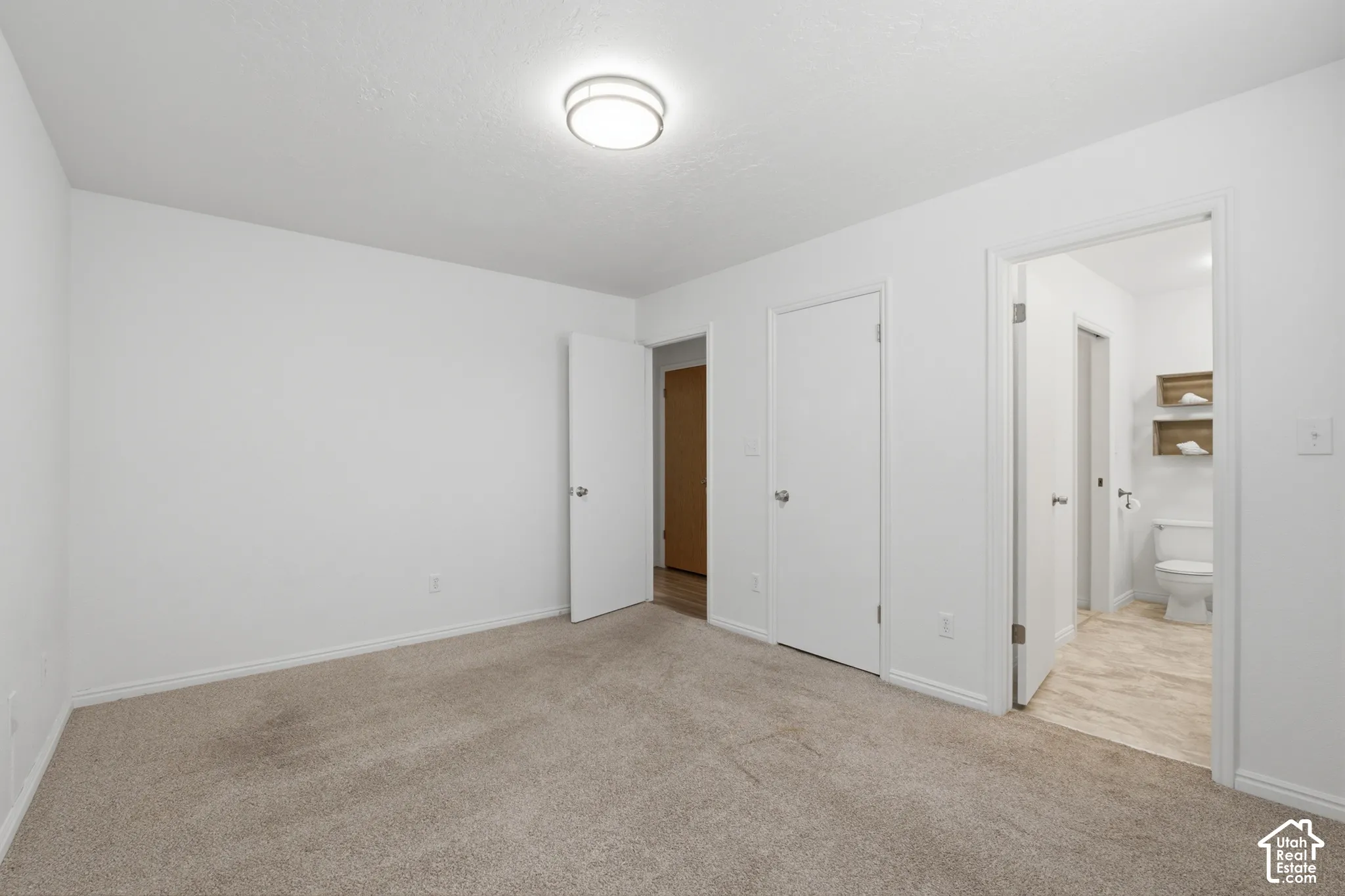 Spacious room featuring neutral carpet flooring, white walls, and a contemporary flush-mount ceiling light