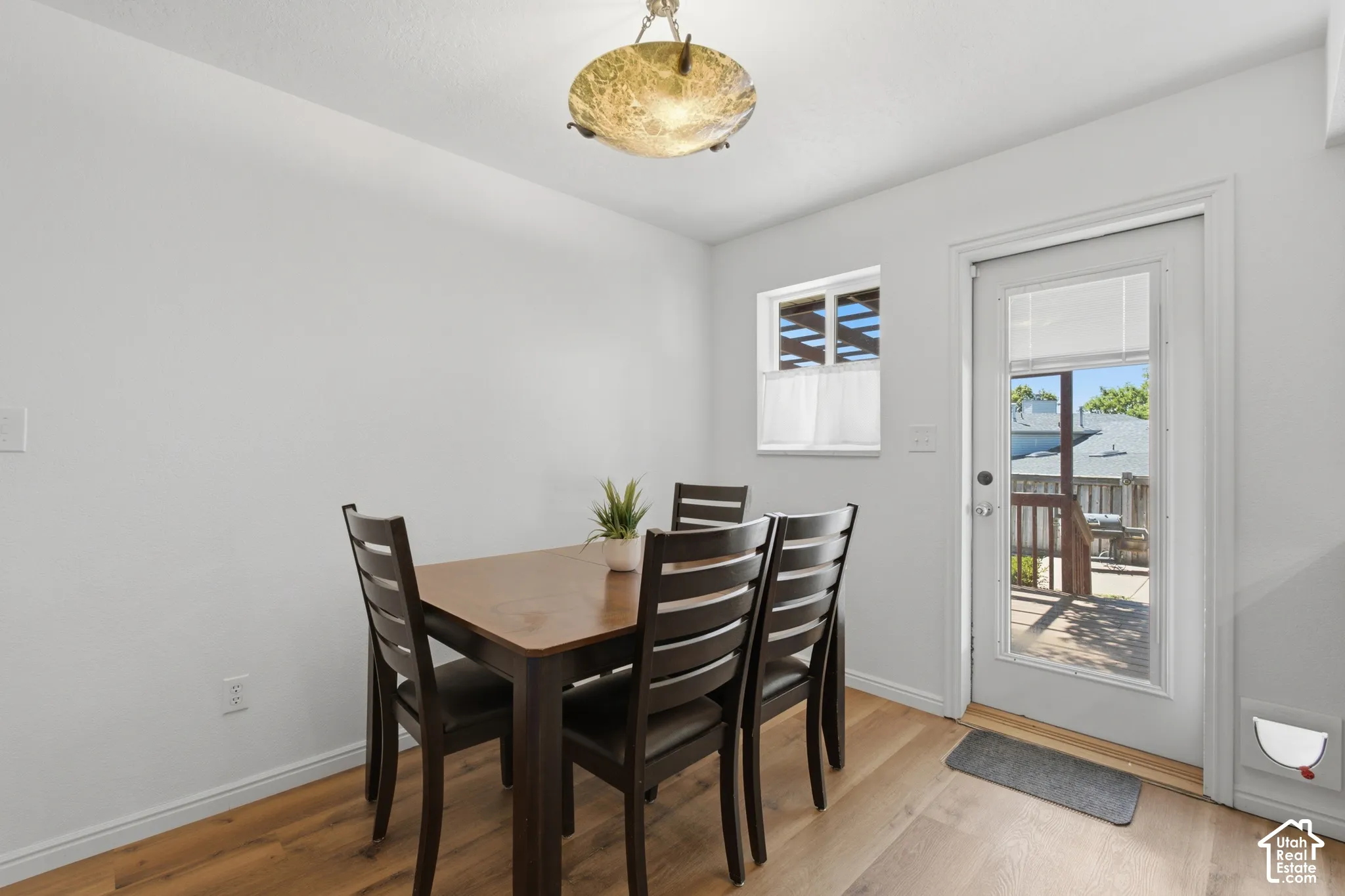 Light wood-finish flooring complements white walls in this dining area