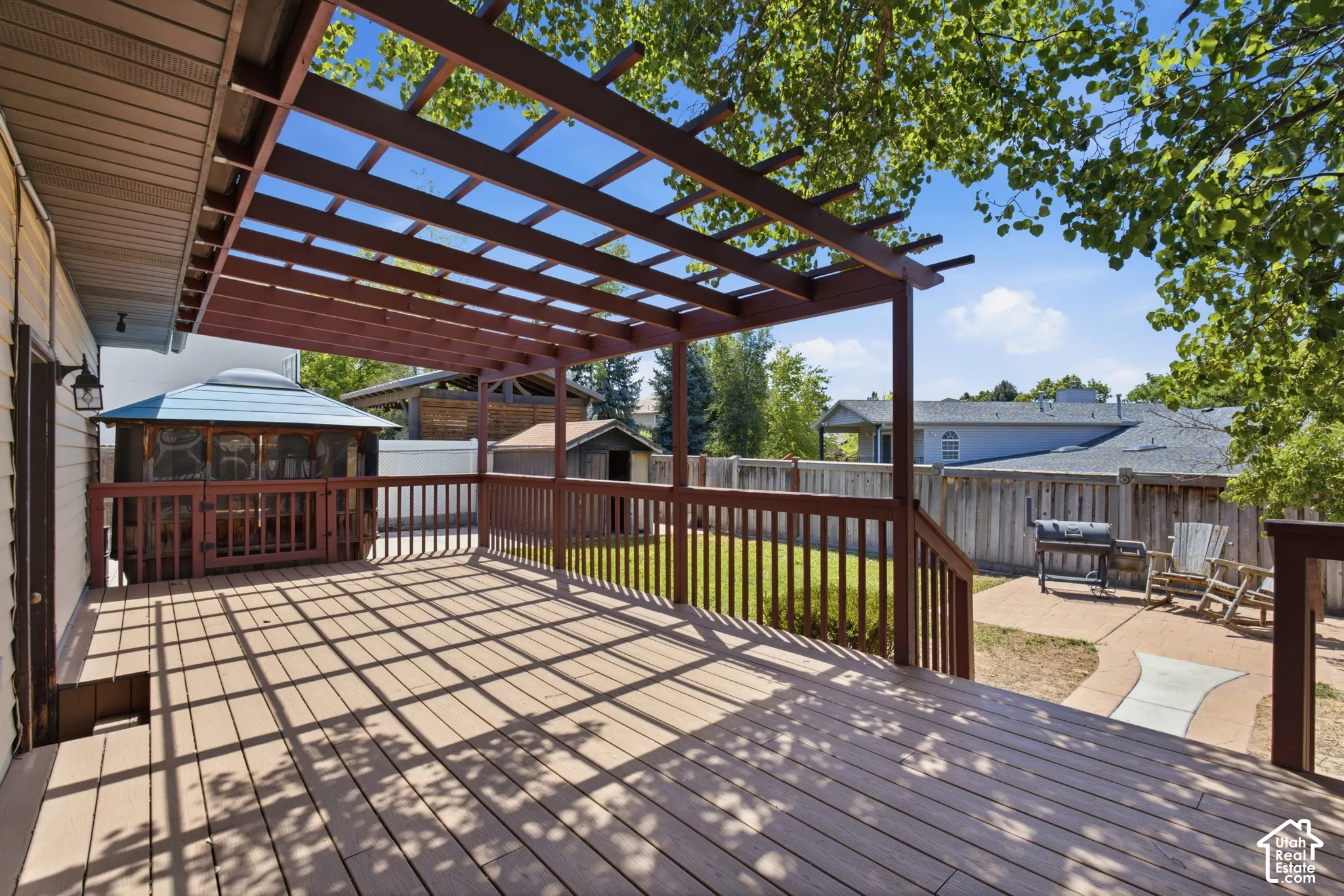Expansive outdoor deck featuring a wooden pergola, full railing, and integrated gazebo with screened panels