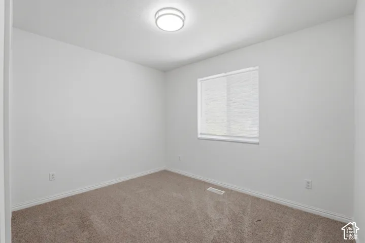Neutral tone carpeted room with white walls and baseboards