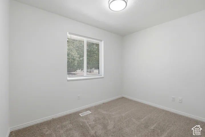 Bright room featuring neutral carpeting, white trim, and a window with blinds