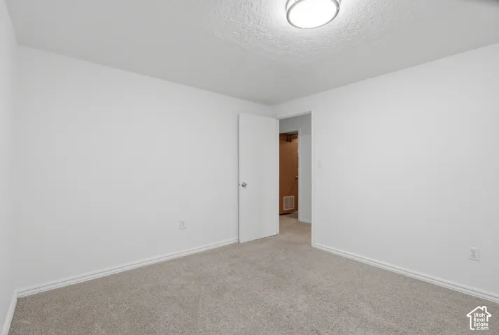 Carpeted room featuring white walls, white trim, and an overhead flush-mount light fixture