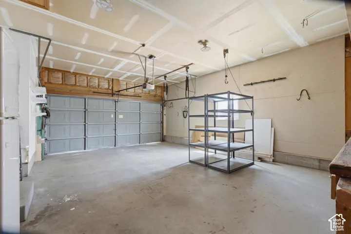 Spacious two-car garage with concrete flooring, automatic garage door opener, and exposed ceiling joists