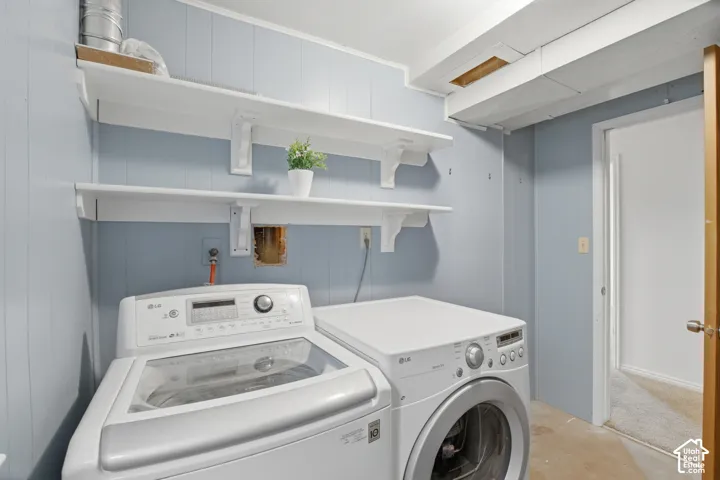 Laundry area featuring wood-paneled walls and a concrete floor