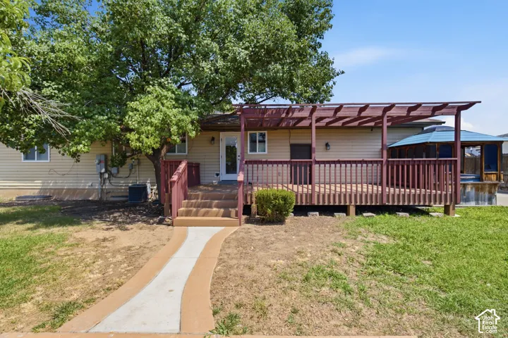 Spacious rear deck featuring a dark wood pergola and railings, a built-in screened gazebo, and a light-colored exterior wall