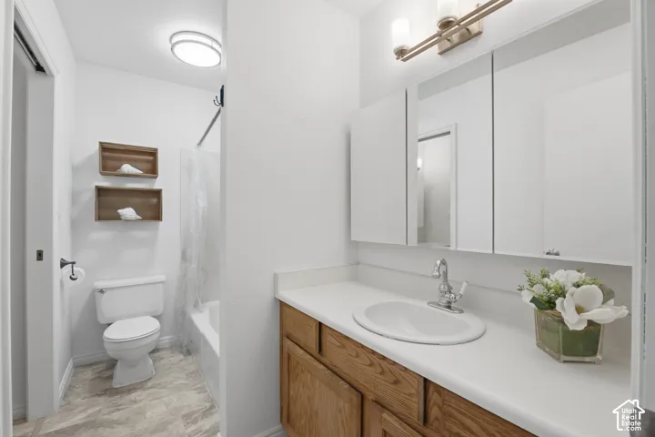 Bathroom vanity featuring a single basin sink, laminate countertop, and wood-finish cabinetry