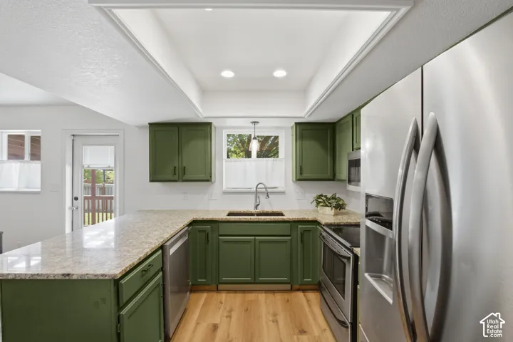 Kitchen featuring green cabinetry, light-toned countertops, stainless steel appliances, wood-finish flooring, and recessed lighting
