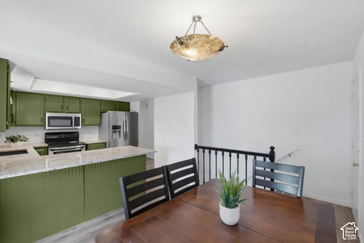 Kitchen and dining area featuring a breakfast bar with granite countertops and green cabinetry