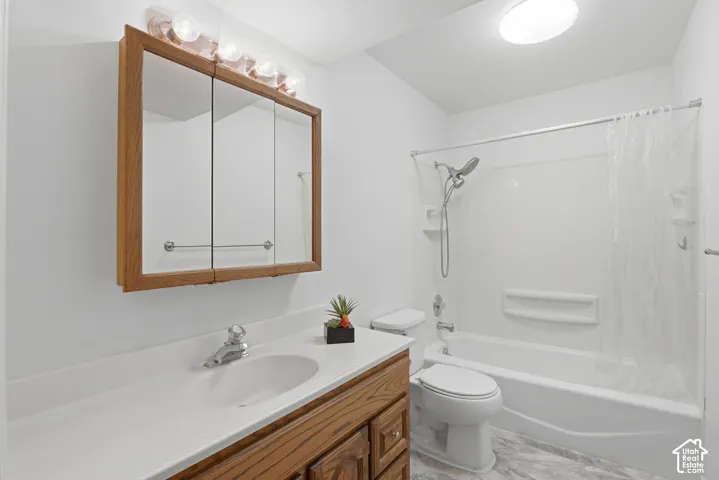 Bathroom featuring a wood-finish vanity with a white countertop and integrated sink, a mirrored medicine cabinet, and a shower-tub combination with a white surround