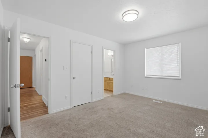 Carpeted room featuring white walls, a flush-mount ceiling light, and a window with blinds