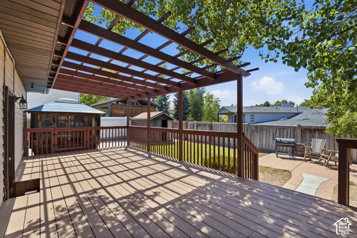 Expansive outdoor deck featuring a wooden pergola, full railing, and integrated gazebo with screened panels