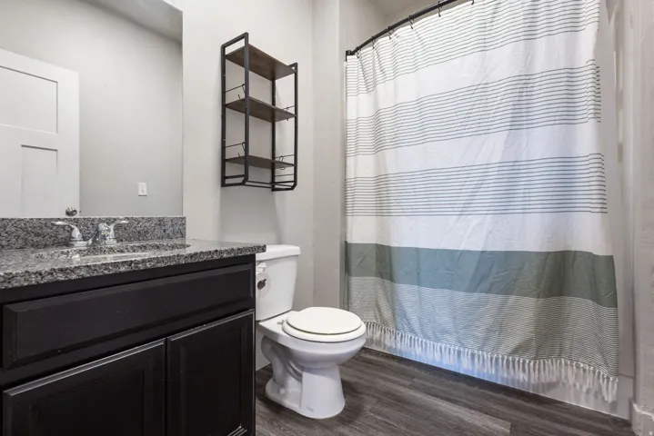Bathroom featuring a dark wood-finish vanity with a speckled countertop, undermount sink, and chrome faucet