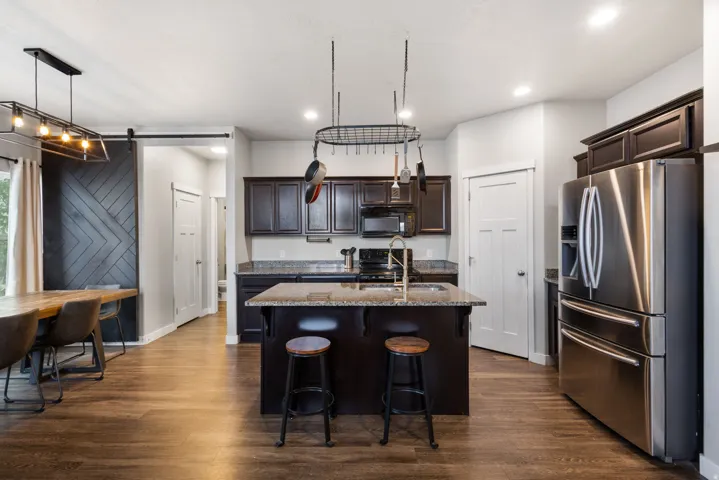 Open concept kitchen featuring an island with counter seating, dark wood cabinetry, and stainless steel appliances
