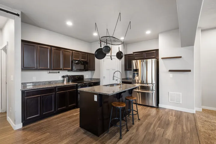 Kitchen featuring wood-finish flooring, dark cabinetry, and speckled countertops