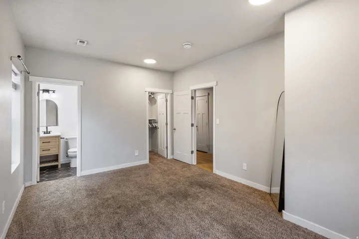 Carpeted room featuring a white interior door, recessed lighting, and a window with a roller shade