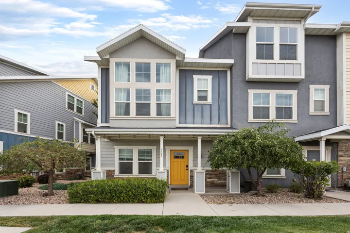Contemporary townhome with a bright yellow entry door, covered porch, large upper-level windows, and a combination of siding and stucco exterior finishes