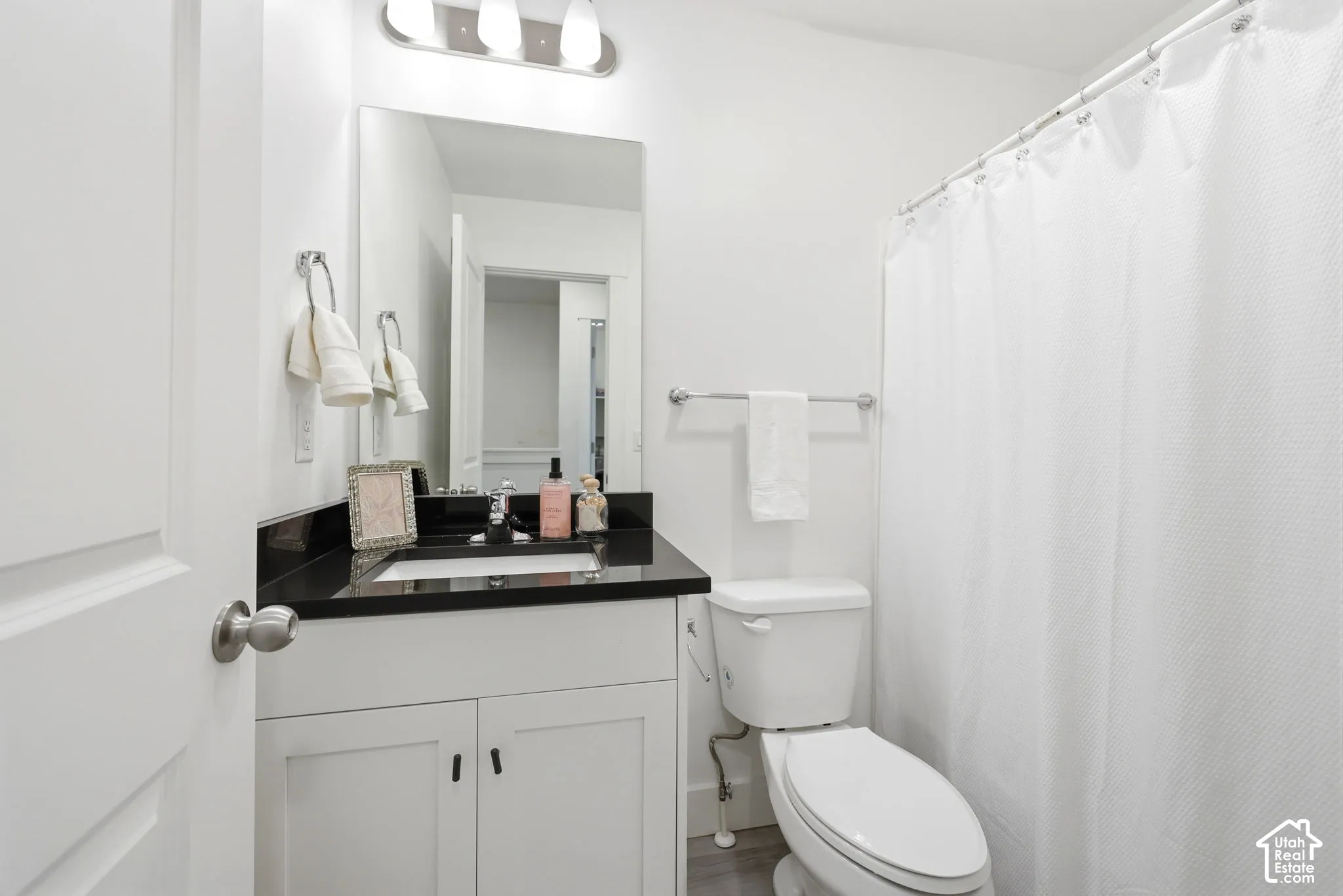 Bathroom featuring a white vanity with black countertop, undermount sink, and chrome fixtures