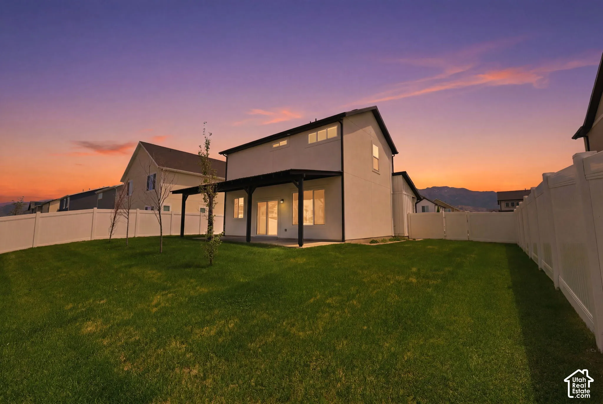 Expansive green lawn with a white vinyl fence enclosing the backyard