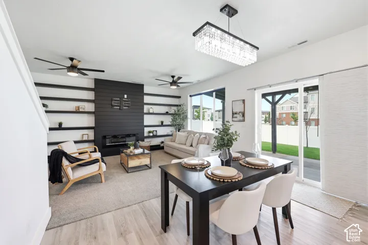 Open-concept living area with wood-finish flooring, a contemporary fireplace feature wall with built-in shelving, a modern rectangular chandelier, and a sliding glass door leading to the backyard