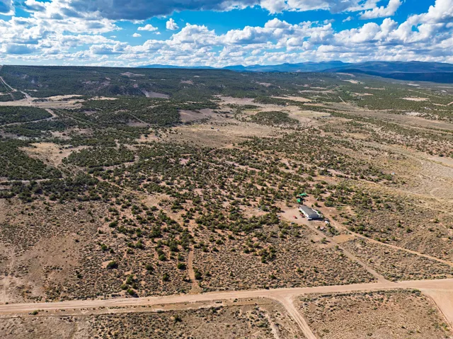 Expansive undeveloped land with scattered vegetation, multiple unpaved roads, and distant mountain ranges