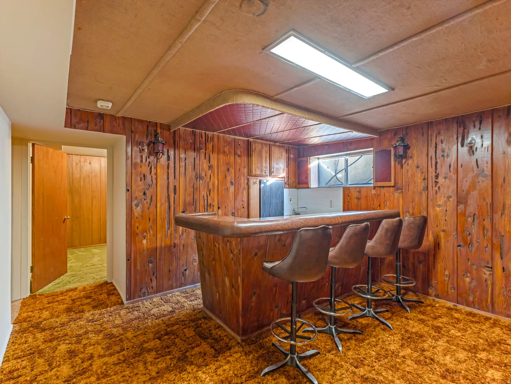 Recreation room featuring wood paneling, a built-in bar, and recessed lighting