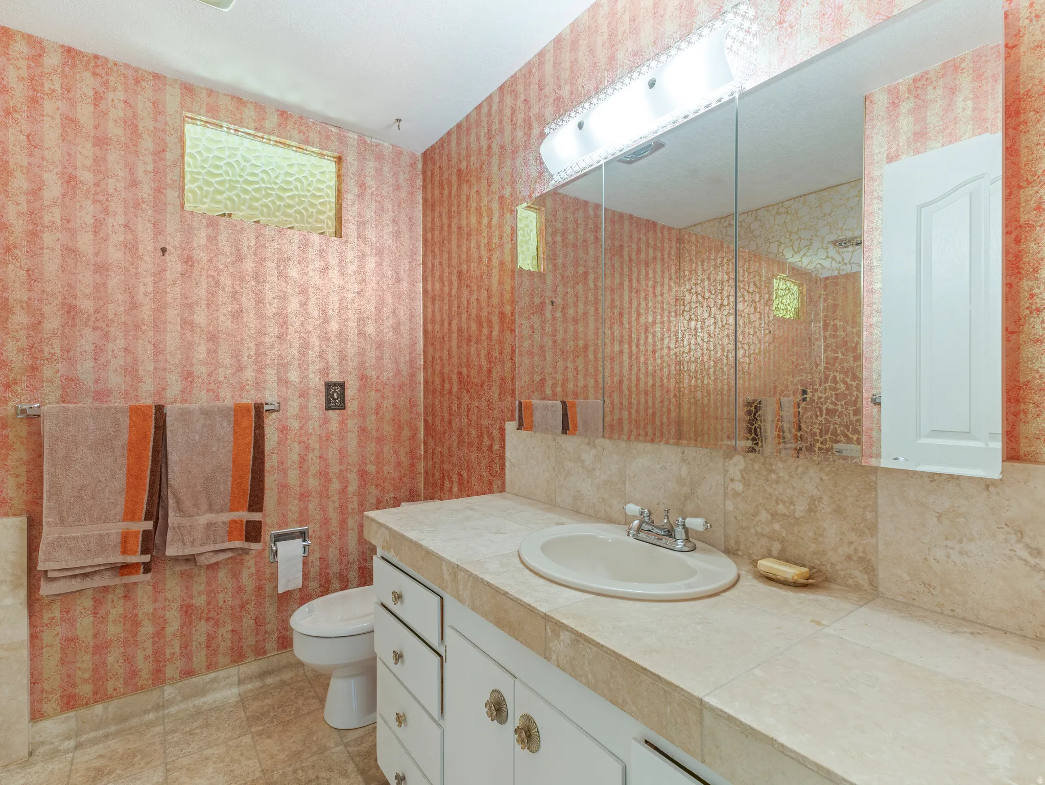 Bathroom featuring a vanity with a drop-in sink, a built-in medicine cabinet, and a large wall mirror