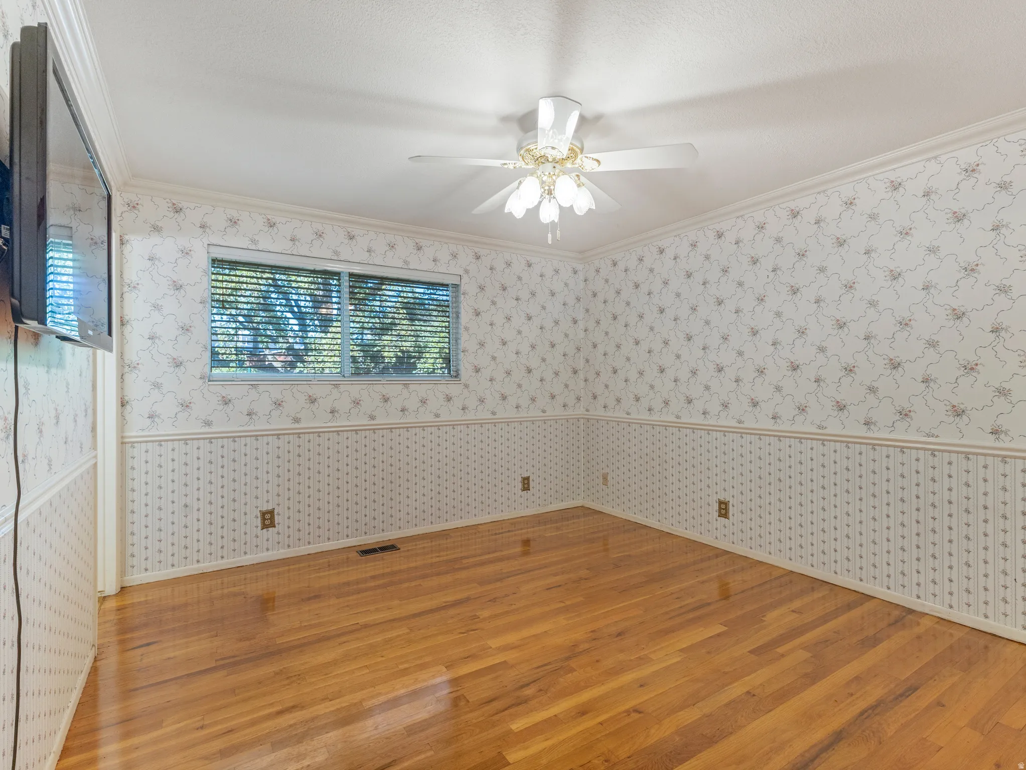Room featuring wood-finish flooring, a ceiling fan with integrated lighting, and a single window with blinds