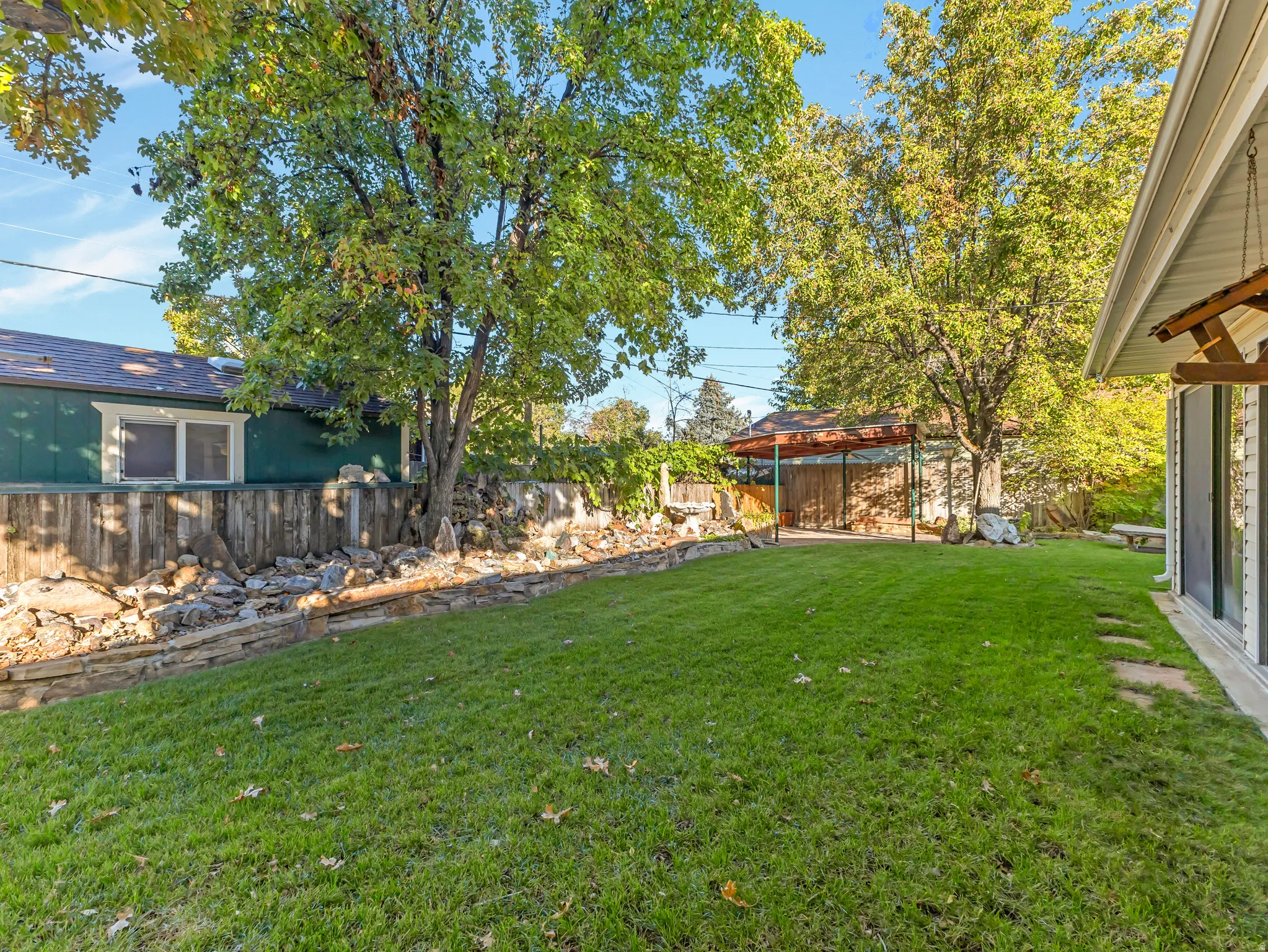Expansive green lawn with mature trees and a stone retaining wall