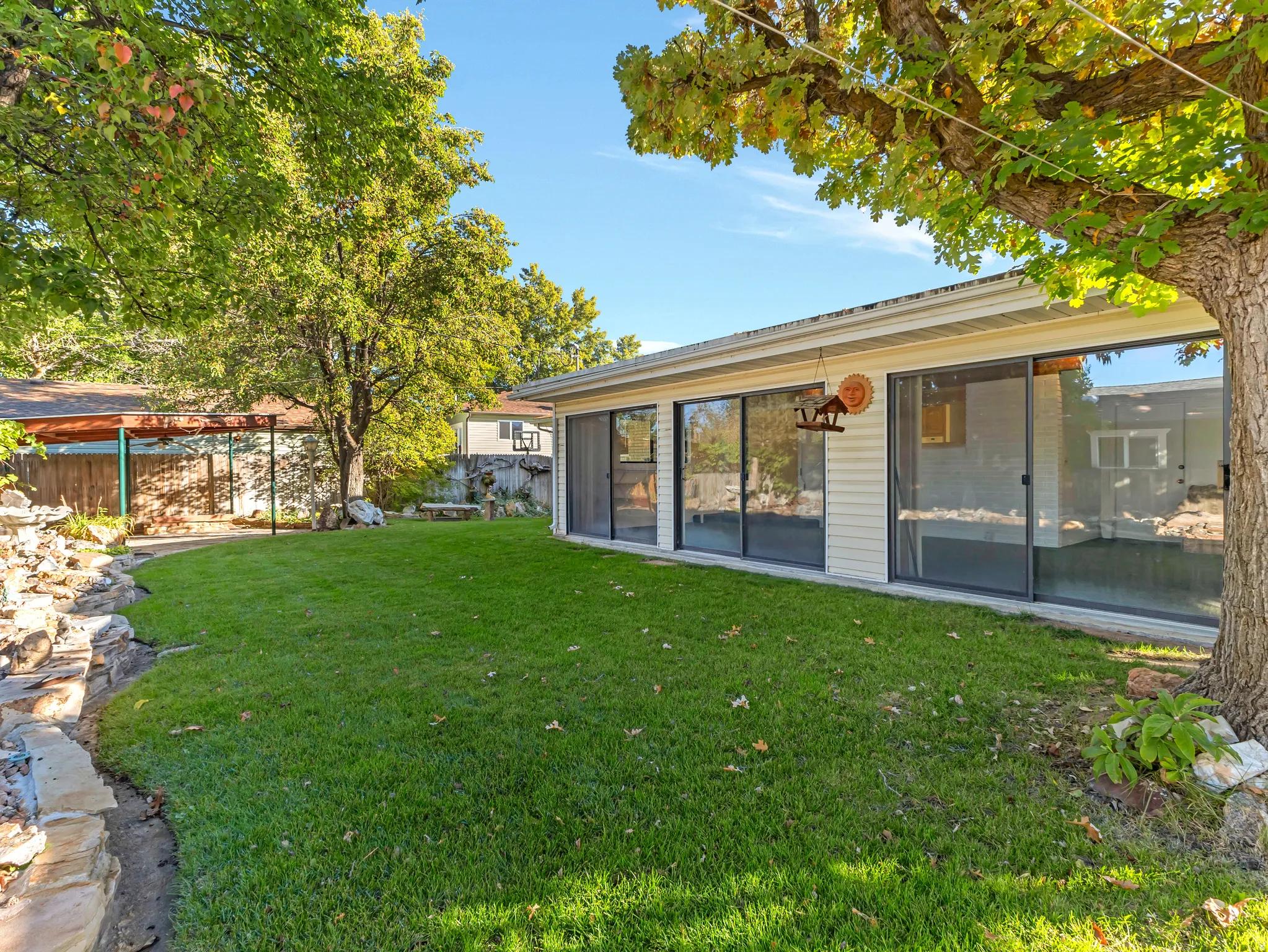 Expansive grassy yard area with mature trees and a stone-edged garden bed