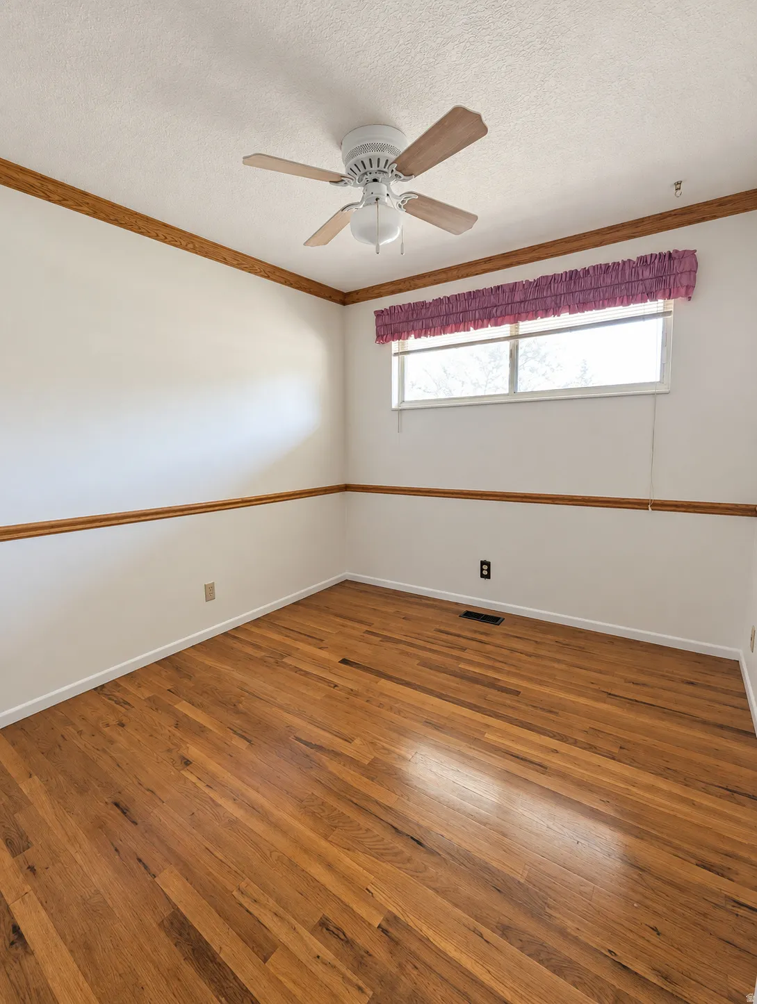Hardwood flooring, white walls, and a ceiling fan with light fixture