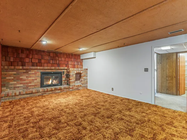 Brick fireplace with a metal insert, a brick hearth, and a shingle-style accent wall