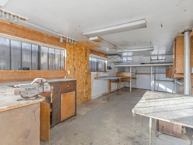 Utility space featuring a concrete floor, built-in shelving, multiple windows, and fluorescent lighting fixtures