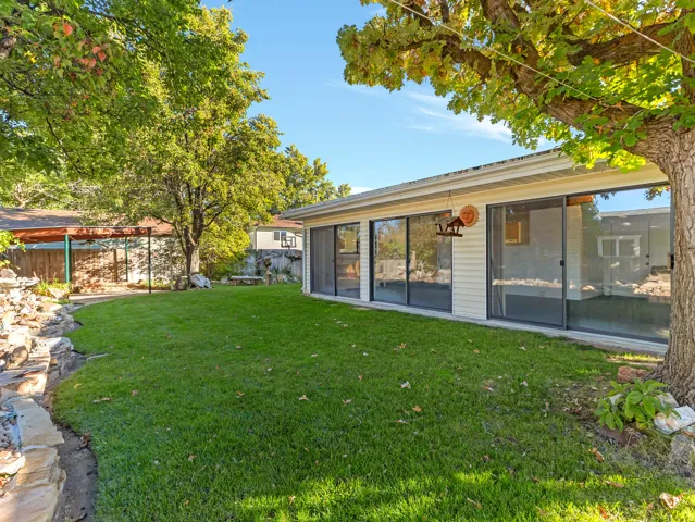 Expansive grassy yard area with mature trees and a stone-edged garden bed