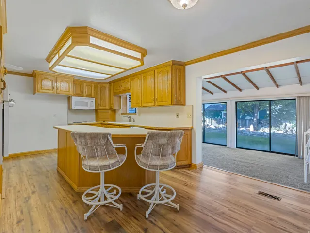 Kitchen featuring wood-finish flooring, wood cabinetry, white countertops, and a built-in microwave
