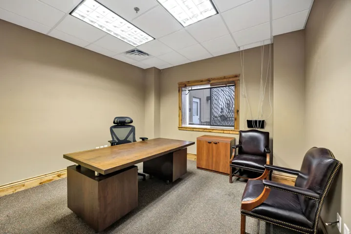 Office space featuring neutral wall tones, carpeted flooring, and a drop ceiling with recessed lighting