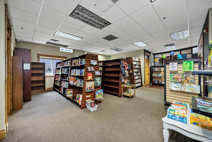 Carpeted interior space featuring extensive built-in shelving units, recessed lighting, and a drop ceiling