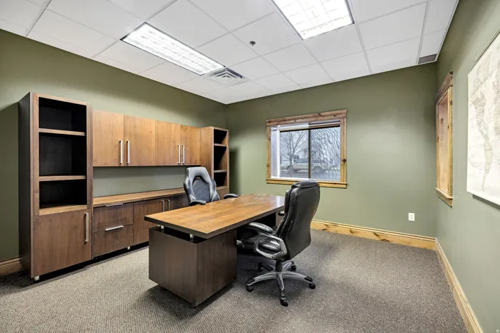 Office space featuring built-in wood-finish cabinetry, a coordinating desk, and a window with wood-finish trim