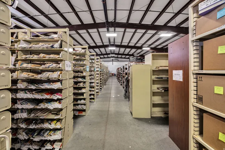 Spacious industrial interior featuring an exposed truss ceiling, concrete flooring, and extensive built-in shelving units
