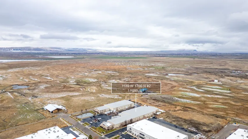 Aerial perspective showcasing multiple commercial structures with expansive undeveloped land surrounding the properties