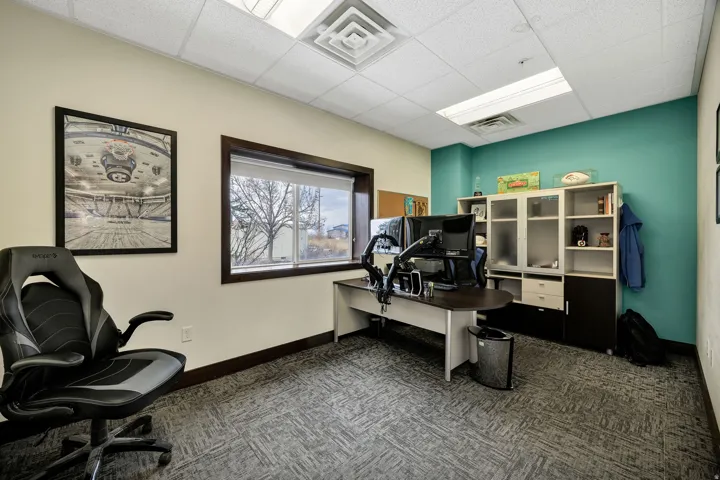 Office space with a drop-tile ceiling, recessed lighting, and a large window with dark trim