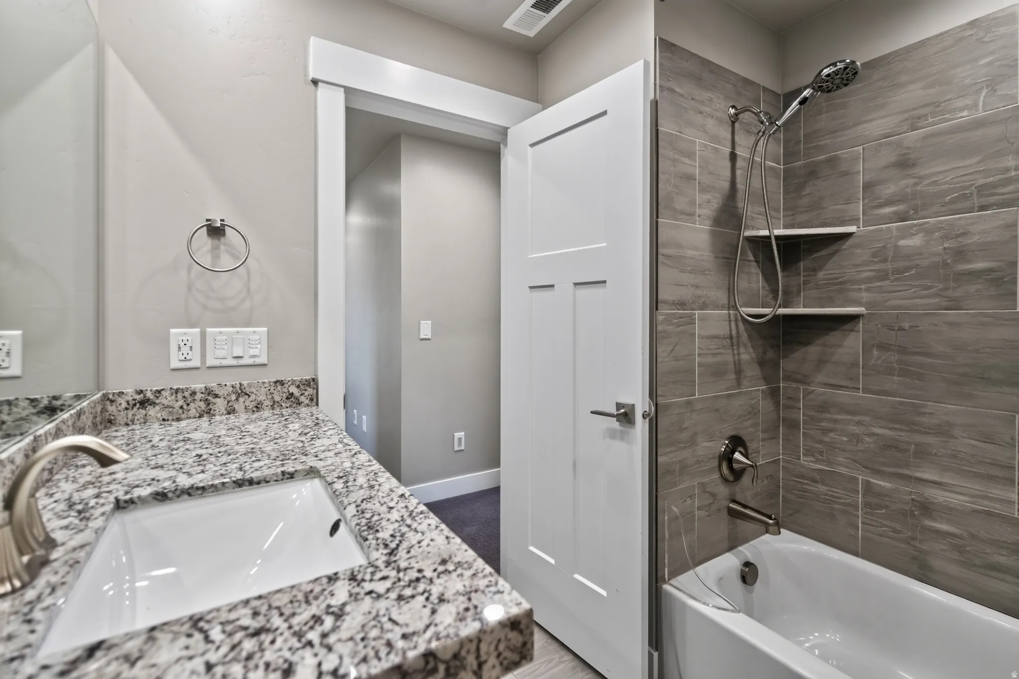 Bathroom featuring a granite-finish vanity with an undermount sink, brushed nickel faucet, and a wall-mounted mirror