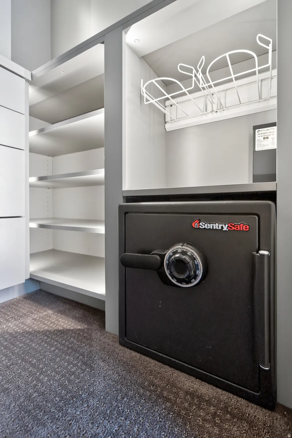 Custom closet system featuring built-in shelving, integrated lighting, and a floor-mounted safe