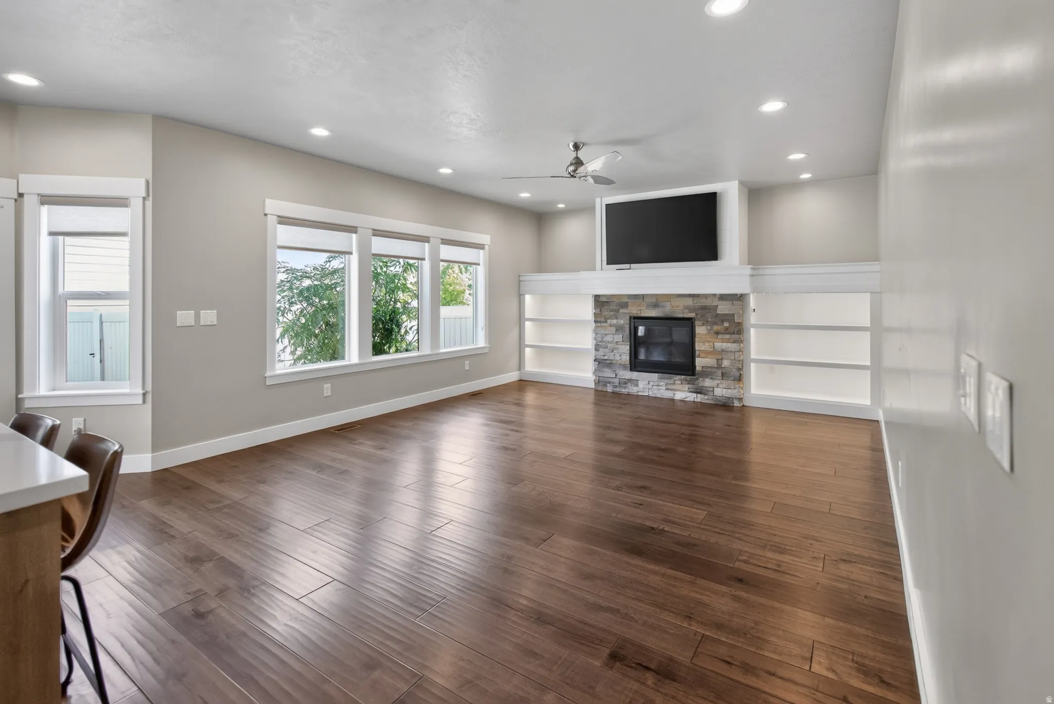 Spacious living area featuring wood-finish flooring, recessed lighting, and a ceiling fan